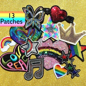 May include: A collection of 13 decorative patches in various shapes, including hearts, stars, a butterfly, a crown, a rainbow, and a musical note. The patches feature sequins and embroidery in vibrant colors, with the text "13 Patches" in a rainbow-colored box.