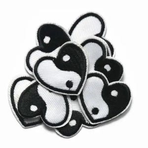 Puede incluir: Un conjunto de parches en forma de corazón yin yang en blanco y negro. Los parches están hechos de tela y tienen un diseño cosido.