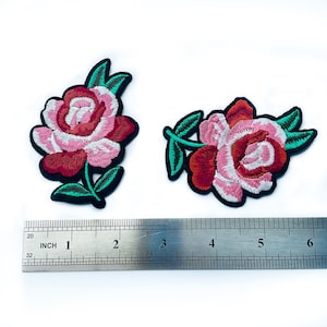 May include: Two embroidered iron-on patches featuring pink and red roses with green leaves. The patches are approximately 2 inches wide and 2 inches tall.