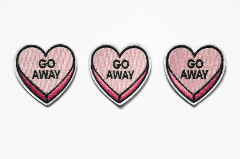 May include: Three pink heart-shaped patches with black outlines and the text "GO AWAY" in black.