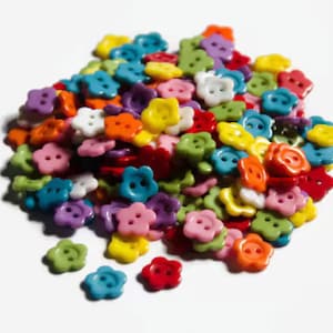 May include: A large pile of colorful flower-shaped buttons in various colors, including red, orange, yellow, green, blue, purple, and white.