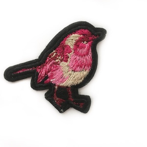 May include: Pink and beige embroidered bird applique patch with black outline.