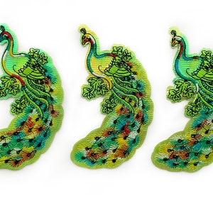 May include: Three green and yellow embroidered peacock patches with iridescent details. The peacocks are facing right and have their tails fanned out.