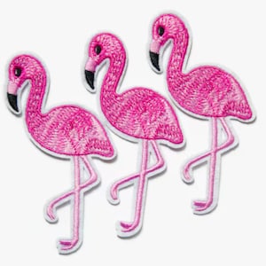 May include: Three pink flamingo iron-on patches. The flamingos are embroidered with pink thread and have black eyes.