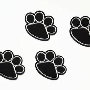 May include: Four black paw print iron-on patches with white outlines.