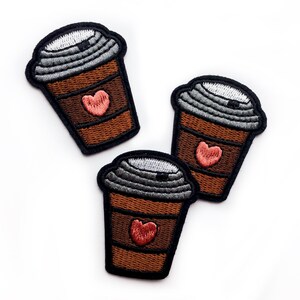 May include: Three embroidered coffee cup patches with a heart on each. The cups are brown with a gray lid and a pink heart.