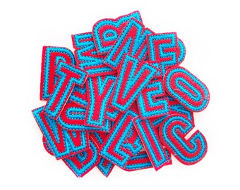 May include: A pile of red felt letters with blue stitching. The letters are all uppercase and are in a variety of fonts.