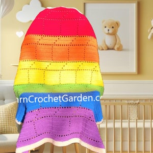 May include: A rainbow colored crochet baby blanket with a white border. The blanket is hanging on a chair in a nursery setting.