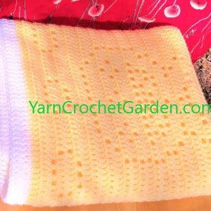 May include: A yellow crochet baby blanket with a white border. The blanket has a delicate, lacy pattern and is made with soft yarn. YarnCrochetGarden.com