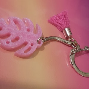 May include: Pink glitter monstera leaf keychain with a pink tassel and a silver key ring.