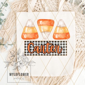 Può includere: Una borsa tote bianca con tre illustrazioni di mais dolce arancione e bianco e uno stendardo a scacchi bianco e nero con il nome "Carter" in arancione.