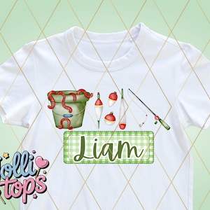 May include: White t-shirt with a green and white checkered box that says "Liam" in green. The shirt also has a bucket with red worms, fishing bobbers, and a fishing rod.
