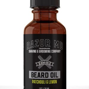 May include: A brown glass bottle of Razor MD beard oil with a black dropper. The label reads "BEARD OIL PATCHOULI & LEMON" and "1OZ/30 ML". The bottle is for shaving and grooming.