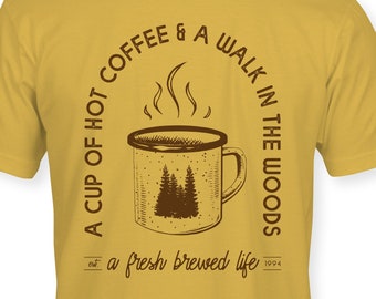 Una taza de café caliente y una camiseta de Walk in the Woods