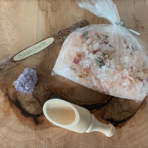 May include: A wooden stick with the word "Gratitude" written on it, a small amethyst crystal, a wooden scoop, and a bag of pink Himalayan salt with dried flowers.