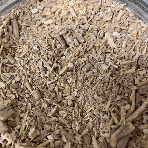 May include: Close-up of a jar filled with dried, light brown, and beige root pieces. The pieces are of varying sizes and shapes, some are long and thin, others are short and thick.