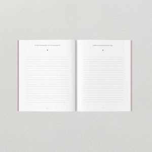 May include: An open notebook with lined pages. The left page has the text "So habe ich festgestellt, dass ich schwanger bin." The right page has the text "Gef&uuml;hle und Gedanken der ersten Tage."