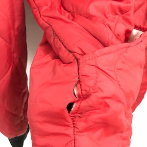 May include: Red quilted jacket with a tear in the seam of the sleeve.