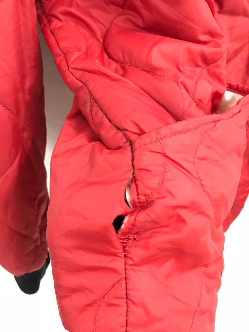 May include: Red quilted jacket with a tear in the seam of the sleeve.