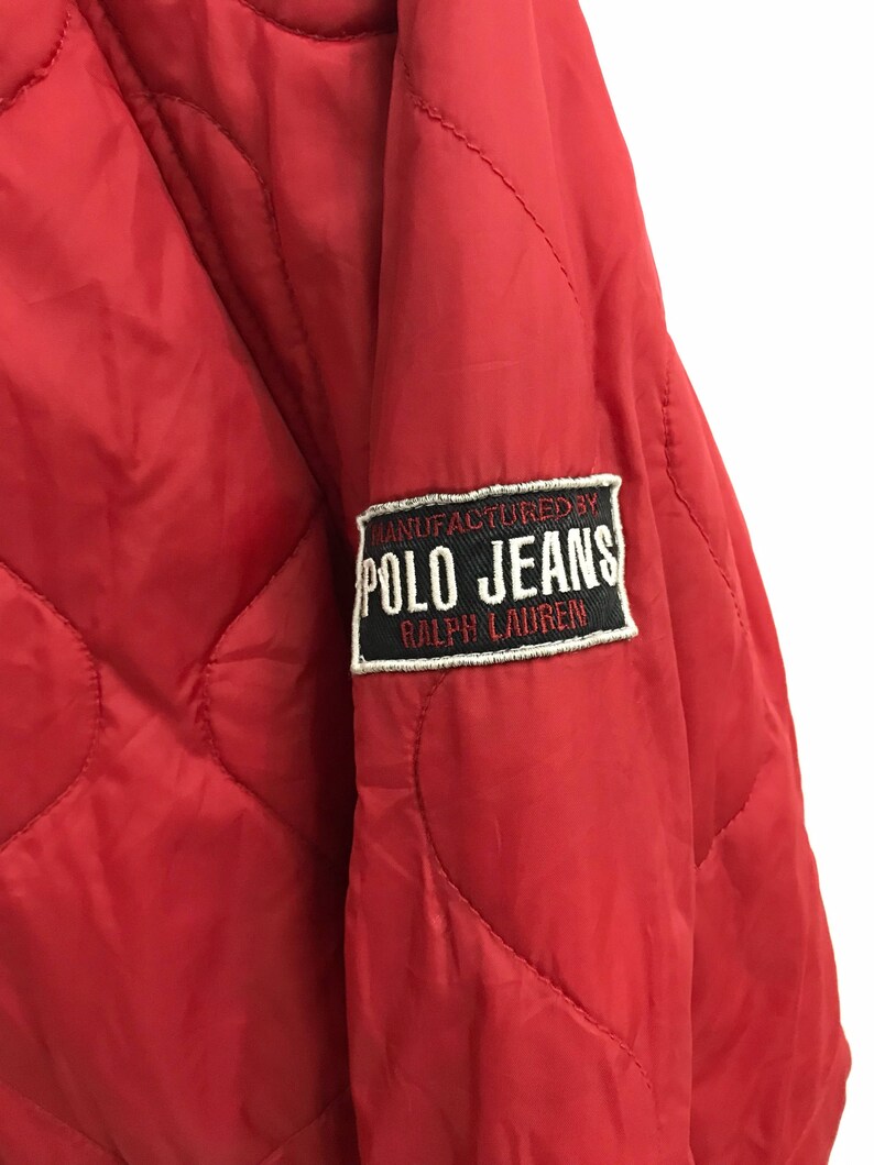 May include: Red quilted jacket with a black and white patch that reads "MANUFACTURED BY POLO JEANS RALPH LAUREN".
