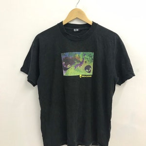 May include: Black t-shirt with a graphic print of a colorful alien face and the text "Beschwa" in yellow.