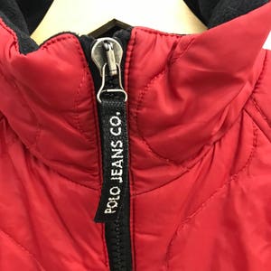 May include: Red quilted jacket with a black zipper and a black "POLO JEANS CO." label on the zipper pull.