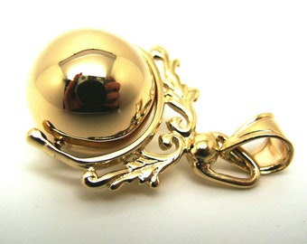 May include: A gold pendant with a round, spinning ball charm. The pendant has a detailed, ornate design with a loop for attaching to a chain.
