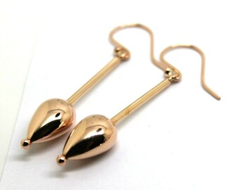 Pode incluir: Um par de brincos de gota de ouro rosa com um caule longo e fino. Os brincos têm um acabamento polido.