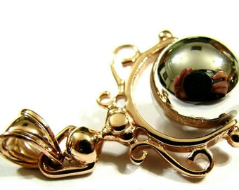 May include: A gold pendant with a silver ball that spins freely. The pendant has a loop for attaching to a chain.