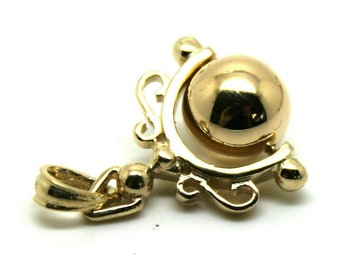 May include: A gold pendant featuring a round ball that rotates within a decorative frame. The pendant has a bail for attaching to a chain.
