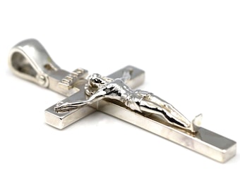 May include: Silver pendant featuring a crucifix with a detailed figure of Jesus Christ. The pendant has a loop for attaching to a chain.