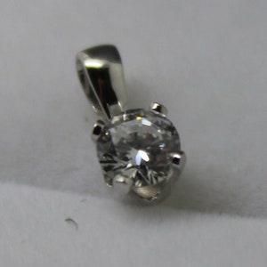 May include: A silver pendant with a clear round gemstone.