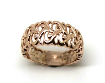 May include: A rose gold filigree ring with a delicate, intricate design. The ring is made of a thin band with a repeating pattern of swirls and curves.