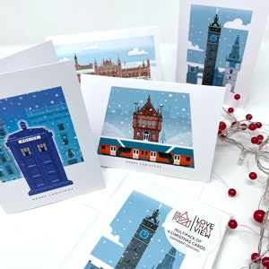May include: A collection of Christmas cards featuring illustrations of buildings in a snowy landscape. One card shows a blue police box, another a clock tower, and others show various buildings. The cards have the text "MERRY CHRISTMAS".