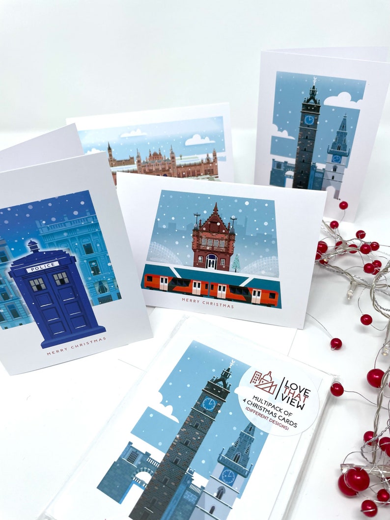 May include: A collection of Christmas cards featuring illustrations of buildings in a snowy landscape. One card shows a blue police box, another a clock tower, and others show various buildings. The cards have the text "MERRY CHRISTMAS".