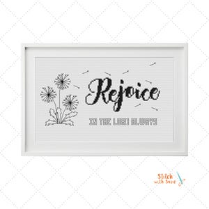 Könnte beinhalten: Ein gerahmtes Kreuzstichmuster mit drei schwarzen Löwenzahnsilhouetten auf der linken Seite und dem Text "Rejoice IN THE LORD ALWAYS" in schwarzer Schrift auf weißem Gitterhintergrund, ergänzt durch kleine, verstreute Löwenzahnsamen.