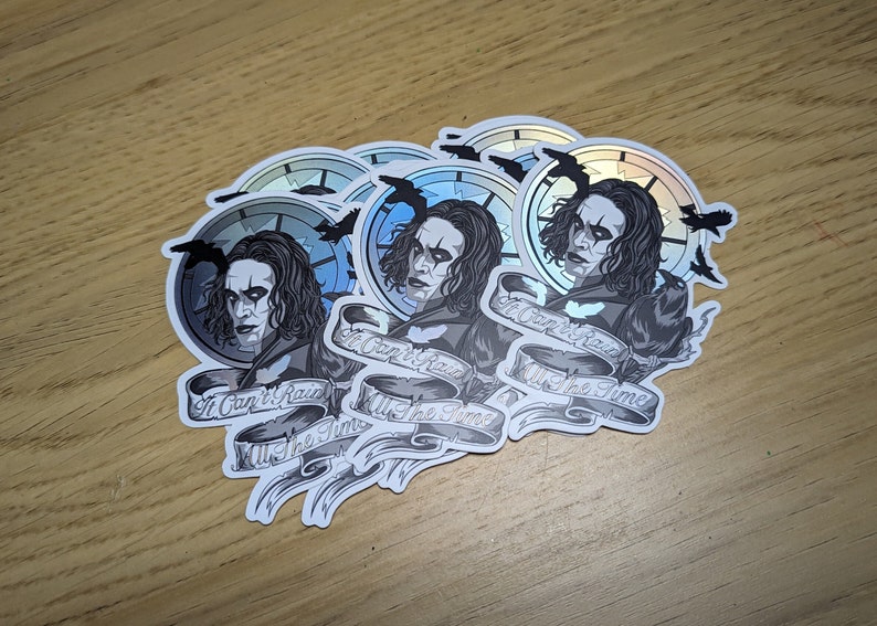 May include: Five silver holographic stickers featuring a black and white illustration of a man with long black hair and a clock behind him. The text on the sticker reads "It Can't Rain All The Time".