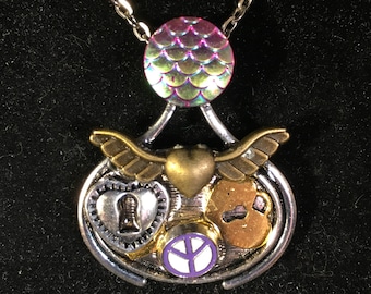 Könnte beinhalten: Eine silberne Kettenkette mit einem Anhänger mit einem Peace-Zeichen, zwei Herzen und einem goldenen Schlüssel. Der Anhänger ist an einem schillernden rosa und grünen Kreis befestigt.