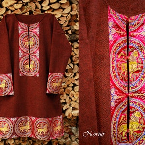 May include: A maroon tunic with gold and red embroidery featuring a repeating pattern of lions. The tunic has a high neckline and long sleeves. The embroidery is detailed and intricate.