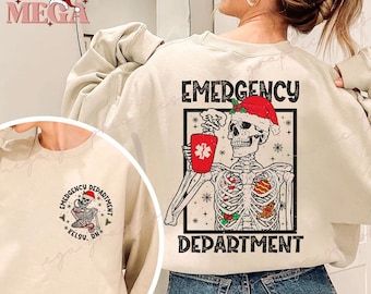 Op de afbeelding: Crèmekleurige sweatshirt met een feestelijk ontwerp. De afbeelding toont een skelet met een kerstmuts, met een rode beker met een medisch symbool. De tekst luidt "EMERGENCY DEPARTMENT" en "KELSY, DN".