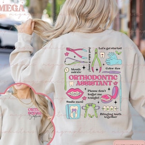 Op de afbeelding: Een lichtbeige sweatshirt met een grafisch ontwerp met verschillende tandheelkundige instrumenten en de tekst "Orthodontisch Assistent". Het ontwerp bevat ook de tekst "Neem het rustig aan!" en "Laten we beginnen!".