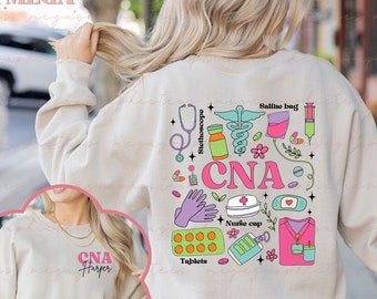 May include: A light beige sweatshirt with a pink and blue design featuring the text "CNA" and various medical illustrations, including a stethoscope, saline bag, nurse cap, and pills. The sweatshirt is customizable.