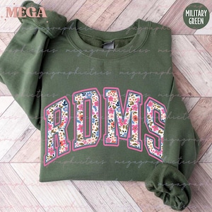 Könnte beinhalten: Ein grüner Pullover mit einem floralen Druck der Buchstaben "RDMS" in Pink.