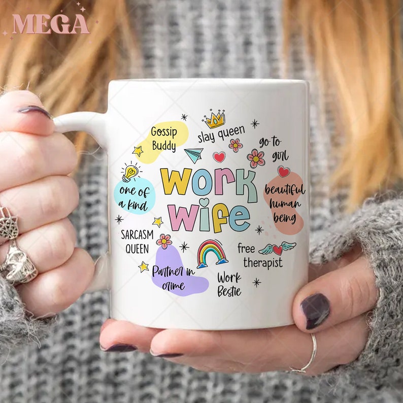 K&ouml;nnte beinhalten: Eine wei&szlig;e Keramiktasse mit einem bunten Design, auf dem "Work Wife" steht und S&auml;tze wie "Gossip Buddy", "Slay Queen", "Go to Girl", "One of a Kind", "Sarcasm Queen", "Partner in Crime", "Free Therapist", "Work Bestie" und "Beautiful Human Being" enthalten sind.
