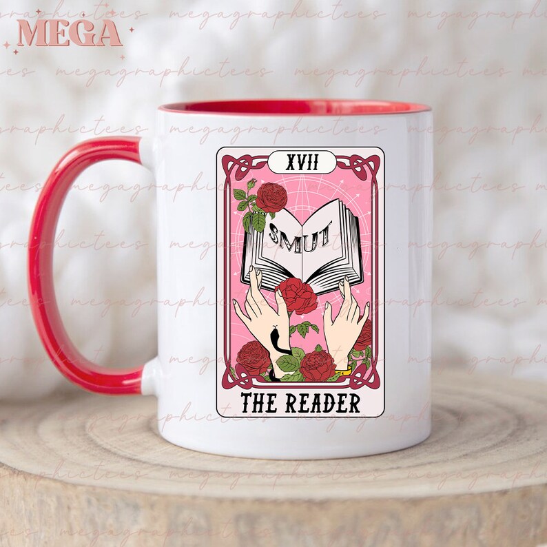 May include: White ceramic mug with a red rim and handle. The mug features a pink tarot card design with the number XVIII and the words "THE READER" and "SMUT" on the card.