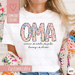 Puede incluir: Camiseta blanca con la palabra "OMA" en letras grandes con estampado floral. Debajo est&aacute;n los nombres: annie, noah, jade, danny y oliver. La camiseta tambi&eacute;n tiene las palabras "Comfort Colors" y "Customizable" en el lateral.