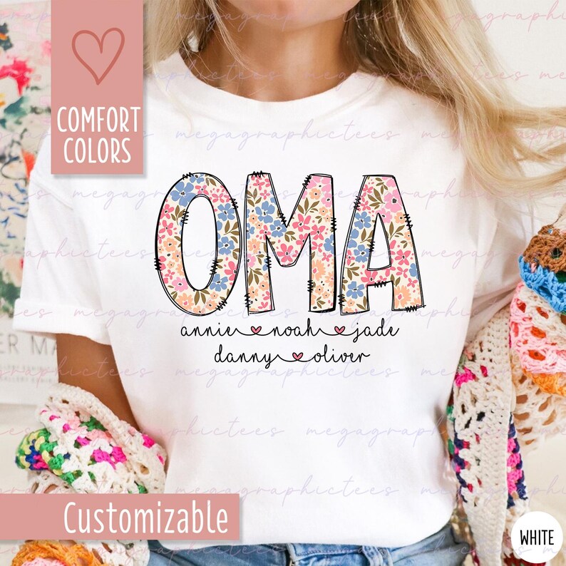 Puede incluir: Camiseta blanca con la palabra "OMA" en letras grandes con estampado floral. Debajo est&aacute;n los nombres: annie, noah, jade, danny y oliver. La camiseta tambi&eacute;n tiene las palabras "Comfort Colors" y "Customizable" en el lateral.