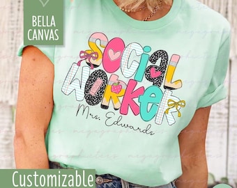 Könnte beinhalten: Hellgrünes T-Shirt mit dem Schriftzug "SOCIAL WORKER" in bunten, verspielten Buchstaben. Das Design beinhaltet Herzen, Bleistifte und einen Apfel. Der Name "Mrs. Edwards" ist darunter aufgedruckt. Das Shirt ist mit "Bella Canvas" und "Customizable" gekennzeichnet.