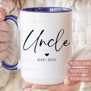 May include: White ceramic mug with a blue rim and handle. The mug has black text that reads "Uncle" with a small heart and "EST. 2025" below. The mug is in a person's hand.