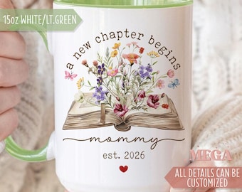 May include: White ceramic mug with a light green interior and handle. The mug features the text "a new chapter begins" and "mommy est. 2026" with a floral design over an open book. The mug is 15oz.